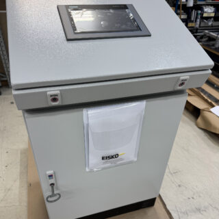 Eiskon valmistama automaatiokeskus, jonka yläosaan on upotettu Siemens SIMATIC HMI -kosketusnäyttö. Keskuksen etuosassa näkyy dokumenttitasku Eisko-logolla.
